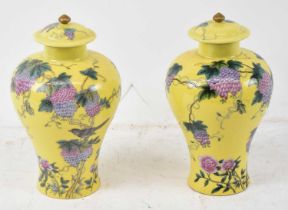 A pair of Chinese porcelain jars with covers, decorated with birds amongst foliage on a yellow