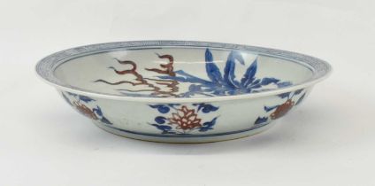 An early 20th century Chinese Ming style underglaze blue and underglaze copper red dish painted to