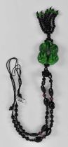 A 20th century Chinese green jade Buddhist lion pendant on a black bead and rose quartz bead