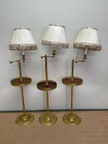A set of three 20th century brass floor lamps with adjustable arms, fluted central columns,