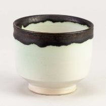 † EMMANUEL COOPER (1938-2012); a small porcelain footed bowl covered in white glaze with copper