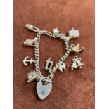 A silver charm bracelet set with several charms, including anchor, typewriter, and watering can,