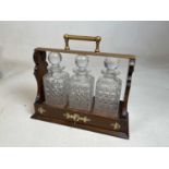 EXETER CYCLING INTEREST; a Victorian oak and brass mounted three bottle tantalus with sliding action