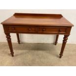 A two drawer mahogany side table with turned and tapered legs, height 69cm, width 104cm, depth