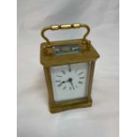 A circa 1900 French brass carriage clock, with swing loop handle and Roman numerals to the white