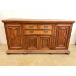 An early 20th century oak sideboard with three central drawers above and flanked by cupboards,