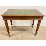 A small leather topped desk with turned fluted decorative legs on small brass castors, height