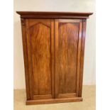 A mahogany double wardrobe with brass and wooden pegs and metal rail, with separate cornice and