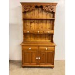 A moden pine kitchen dresser (one piece) with fret carved detail to top, two plate racks and drawers