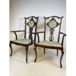 A pair of mahogany elbow chairs with upholstered seats.