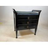 An early 20th century ebonised piano stool with padded seat and three sheet music drawers beneath.