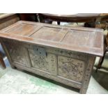 An early 18th century oak coffer with triple panel hinged lid, carved front detail, and raised on