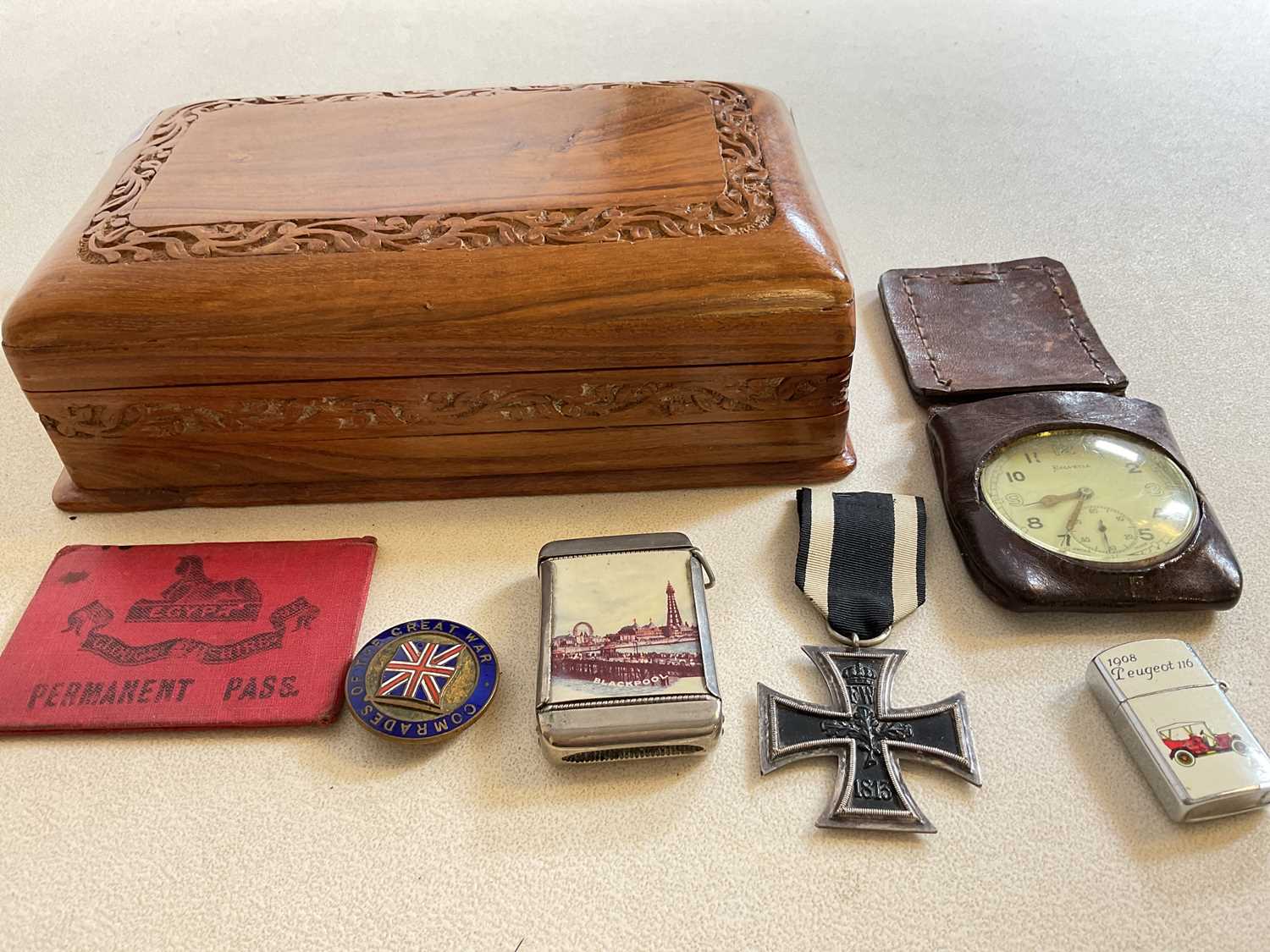 A small carved box, an Iron Cross, base metal vesta case, pocket watch, and badge.