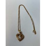 A yellow metal and diamond heart shaped pierced pendant set with a pear cut stone and 13 round