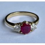 An 18ct yellow gold ruby and diamond three stone ring, with central oval ruby flanked by twin