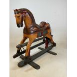 A small carved and painted rocking horse on a metal rocker and wooden base, height 85cm, width 90cm,