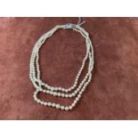 A graduated three strand hand tied cultured pearl necklace with silver clasp, length 46cm.