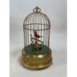 A 20th century brass bird cage automaton with yellow and red feathered birds with foliage, winding