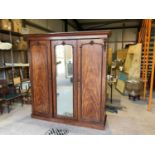 A mahogany triple wardrobe with one mirrored door, interior fitted pegs and boot drawer, five slides