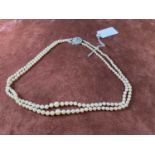 A two strand graduated cultured pearl necklace, set with a 9ct white gold pierced circular clasp