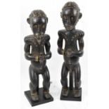 A pair of Fang, Gabon figures both with brass stud detail and mounted on contemporary plinth stands,