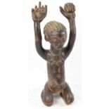 A Lega, Democratic Republic of Congo, figure modelled with arms raised aloft and kneeling, height