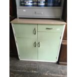 A 1950s kitchen cabinet with formica top above an arrangement of three cupboard doors and single