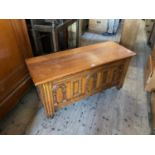 A reproduction oak blanket chest of rectangular form with carved and panelled front, terminating