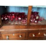 A collection of Victorian and later cranberry glass, predominantly glasses, a lidded jar, etc.