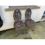 A pair of reproduction cast iron garden chairs with pierced backs representing a male figure (2)