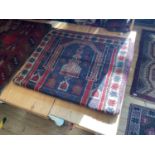 An Afghan rug with stylised decoration of a building on a predominantly blue and red ground.