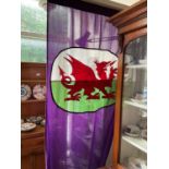 A vintage Welsh flag representing a passant dragon, in shades of purple, white, green and red.