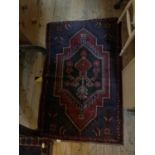 A decorative Eastern rug with floral decoration on a red and blue ground, 134 x 86cm.