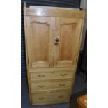 A Continental pine linen press with three base drawers and pair of cupboard doors enclosing two