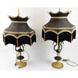 A pair of ornate gilt metal and bronze effect decorative three branch table lamps with shades,