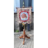 A Victorian firescreen, the beaded tapestry panel suspended from a brass rail and brass column on