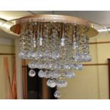 A modern ceiling mounted chandelier suspending numerous glass droplets.