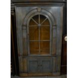 A contemporary distressed pale blue bookcase on cupboard on arched glazed door above two