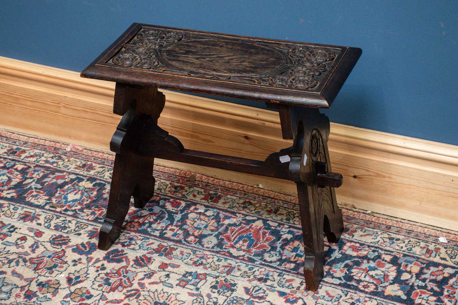 An early 20th century carved oak trestle style coffee table, length 55cm depth 29cm, height 49cm.