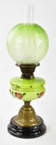 An early 20th century oil lamp, the globular green and clear frosted glass shade decorated with