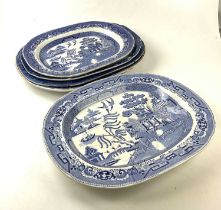 Five 19th century blue and white meat plates with meat drainers, predominantly 'Willow' pattern,