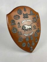 An easel back presentation shield with various cap badges and militaria crests including 11th Armour