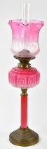 A late Victorian oil lamp, the cranberry and clear glass shade with panelled detail and etched