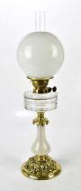 A cut glass two tier vessel oil lamp with fluted brass column sitting on a black round ceramic