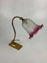 An early 20th century brass adjustable reading lamp, with cranberry and frosted glass shade,