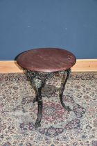 A cast iron pub table decorated with the green man, with later top, height 73cm, diameter 63cm.