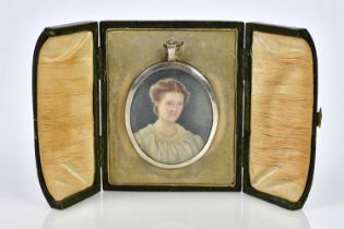 An early 20th century watercolour on ivory, portrait miniature of a girl wearing a white nightdress,