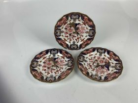 CROWN DERBY; three circular cabinet plates with floral Imari decoration, diameter 22cm (af).