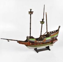 A painted wooden three masted ship on base, height 57cm.