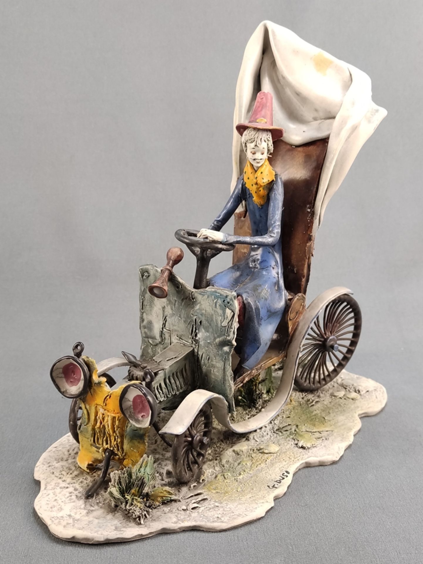 Ceramic figure, Lo Scricciolo, person sitting on a car, coloured design, signed F. Duso on the base